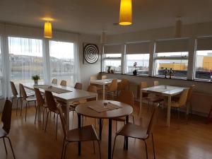 jadalnia ze stołami, krzesłami i oknami w obiekcie Hotel Hvammstangi Guesthouse w mieście Hvammstangi
