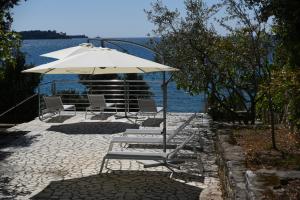 grupa krzeseł i parasol obok wody w obiekcie Buric House - Apartment Vintage w Rovinj