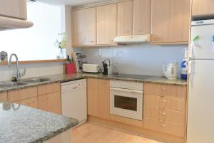 - une cuisine avec des placards en bois et un réfrigérateur blanc dans l'établissement Apart Port Pals Duplex, à Pals