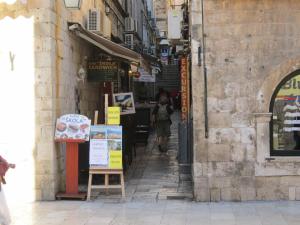 a woman walking down an alley in a city at Apartments Giron in Dubrovnik