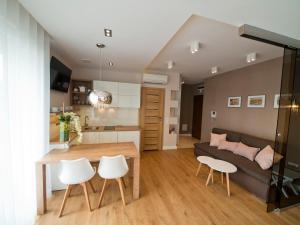 a kitchen and living room with a table and a couch at Apartament Aria Studio in Kraków