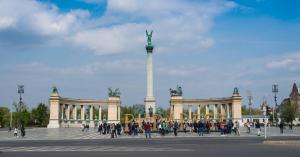 una folla di persone che camminano davanti a un monumento di Home, far away from Home a Budapest
