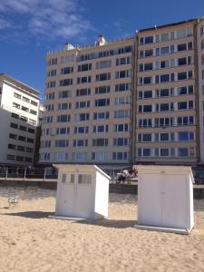2 cabanes de plage sur le sable en face d'un bâtiment dans l'établissement appartement seafront, à Ostende