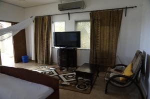 a living room with a bed and a television at Ramaya Auberge Espagnole in Grand-Popo
