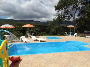 a swimming pool with chairs and umbrellas next to a pool at Pousada Florada na Serra in Serra do Cipo