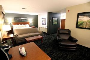 a hotel room with a bed and a couch and chair at C'mon Inn Grand Forks in Grand Forks