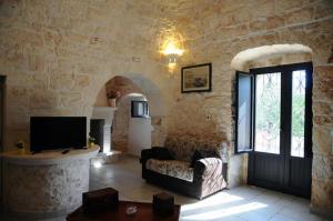 ein Wohnzimmer mit einem Sofa und einem TV in einer Steinwand in der Unterkunft Tenuta Arcangelo in Ceglie Messapica