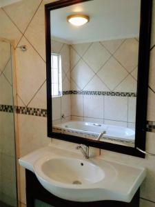 La salle de bains est pourvue d'un lavabo, d'un miroir et d'une baignoire. dans l'établissement Cottage Guesthouse, à Pretoria
