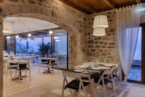 a dining room with tables and chairs and a stone wall at Aegila Boutique Hotel in Éxo Nímfion