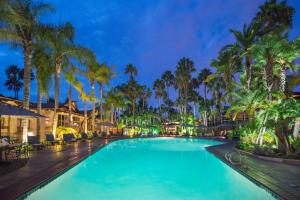 a swimming pool with palm trees at night at Humphreys Half Moon Inn in San Diego