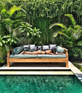 a person laying on a couch next to a pool at Villa Niluh in Canggu