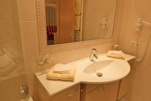 ein Badezimmer mit Waschbecken und Spiegel in der Unterkunft Hotel Angelika in Sankt Anton am Arlberg