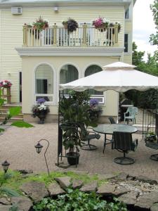 a patio with a table and an umbrella in front of a house at Bedham Hall B&B in Niagara Falls