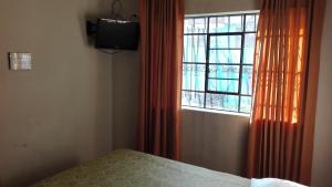 Dormitorio con ventana, cama y TV en Hostal Killaymi, en Arequipa