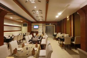 a dining room with tables and chairs and a television at Hotel Millennium in Guwahati