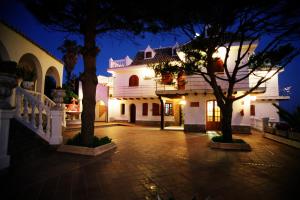 a large white building with trees in a courtyard at night at Hostal Mar de Frente in Los Caños de Meca