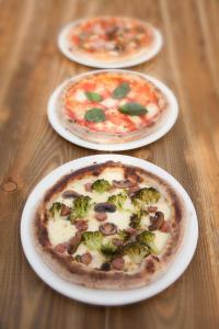 three pizzas sitting on plates on a wooden table at The First Hurdle Guest House in Chepstow