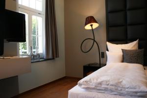 a bedroom with a bed with a lamp and a television at Hotel Rosenmeer in Mönchengladbach