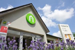 a company logo on the side of a building with purple flowers at Campanile Saint-Avold in Saint-Avold