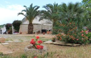 a garden with flowers and palm trees and a building at Masseria Gianecchia in Cisternino
