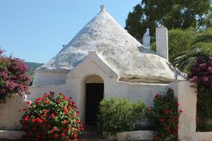 a small chapel with red flowers in front of it at Masseria Gianecchia in Cisternino