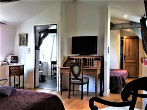 a bedroom with a desk with a television and a bed at Aux Rives de Honfleur in Berville-sur-Mer