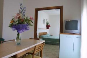 una sala de estar con una mesa con un jarrón de flores en Residence Mini Sayonara, en Lido di Jesolo