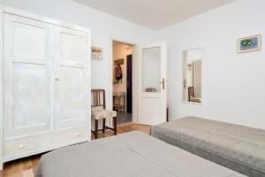 a white bedroom with two beds and a closet at Stone house Apartment Pelago in Jelsa