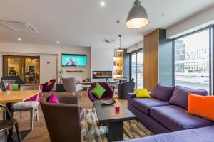 a living room with a purple couch and tables and chairs at Campanile Metz Centre - Gare in Metz