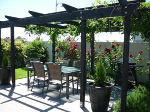 a patio with a table and chairs under a pergola at Courtenay B & B in Kaiapoi