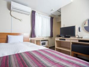 a hotel room with a bed and a flat screen tv at FLEXSTAY INN Shinagawa in Tokyo