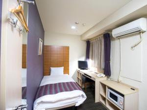 um quarto de hotel com uma cama e uma secretária em FLEXSTAY INN Shinagawa em Tóquio