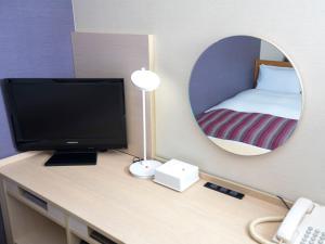 a room with a desk with a television and a mirror at FLEXSTAY INN Shinagawa in Tokyo
