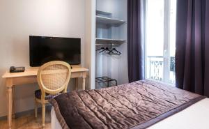 a bedroom with a bed and a desk with a television at Hôtel Du Brésil in Paris