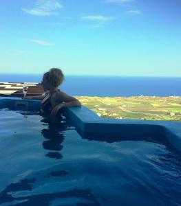 a woman sitting in a swimming pool with a glass of wine at Belle Etoile Villas in Imerovigli