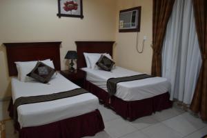 a hotel room with two beds with white sheets at Nojoom Yanbu in Yanbu
