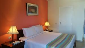 Xperience Hill-Top Beach Resort في شرم الشيخ: غرفة نوم مع سرير بجدران برتقالية ومصباحين