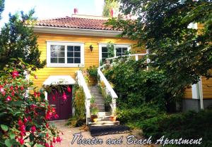 una casa amarilla con una escalera blanca delante de ella en Theater and Beach Apartment en Tampere