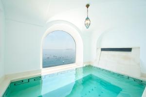 an indoor swimming pool with a window overlooking the ocean at Hotel Marincanto in Positano