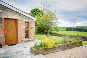 een stenen huis met een houten deur en een tuin bij The Bothy Self Catering Accommodation in Rousky