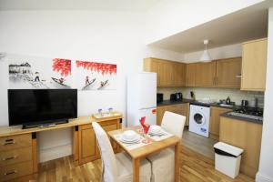a kitchen with a table with chairs and a television at Wellesley Road Apartments in Croydon