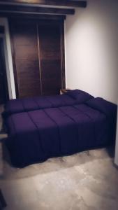 a large purple bed in a room with a door at Posada de Momo in Benamejí