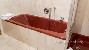 ein Bad mit einer roten Badewanne in einem Zimmer in der Unterkunft Hotel Buchberg in Schönsee