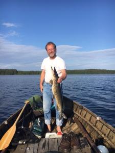 un hombre sosteniendo un pez en un barco en Lomatila Ollila Bungalows en Kerimäki