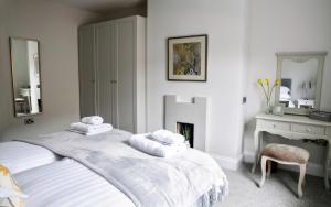 a white bedroom with a bed with towels on it at Spa Apartments in Harrogate