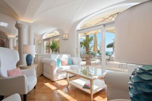 a living room with white furniture and a glass table at Hotel Marincanto in Positano