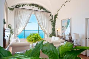 a living room with white furniture and a large window at Hotel Marincanto in Positano