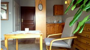 a kitchen with a table and a chair and a clock at Pokoje Przy Plaży in Mielno