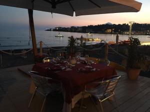 a table with chairs and an umbrella and the ocean at Hotel Tirreno in Sapri