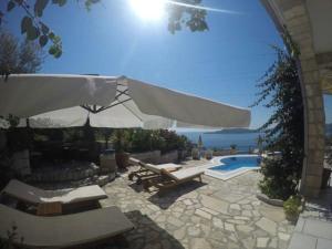 patio z basenem, parasolem i krzesłami w obiekcie Villa Royal Dream w miejscowości Sveti Stefan